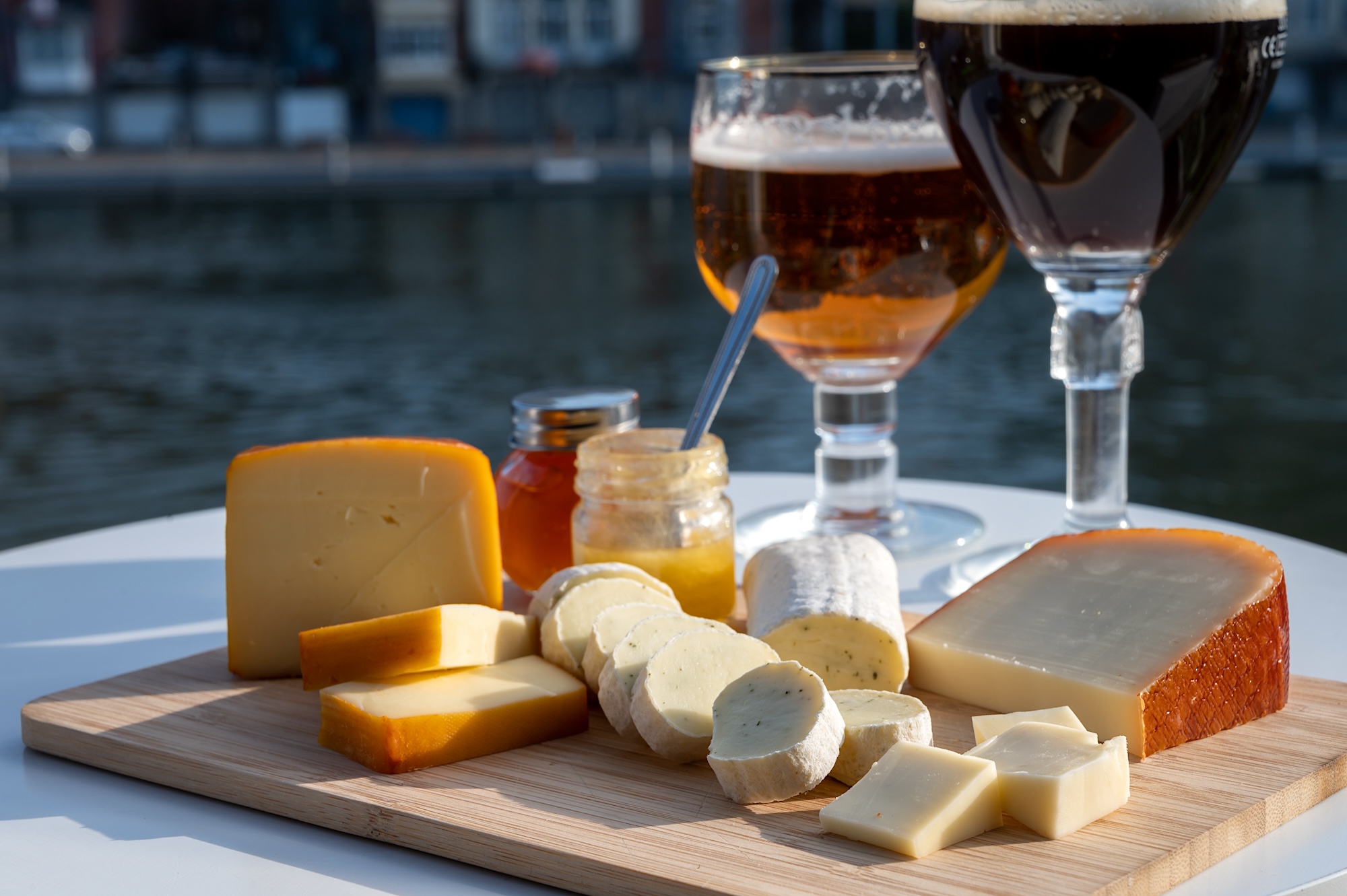 Glass of Belgian abbey beer and tasting of cheeses made with trappist beer and fine herbs with view on Maas river in Dinant, Wallonia, Belgium